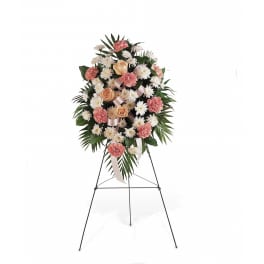 Standing floral spray with pink carnations, white daisies, and peach roses on an easel
