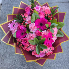 Pink bouquet with roses, gerbera daisies, and carnations in decorative wrap