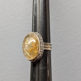 Oval gemstone ring on a dark display stand