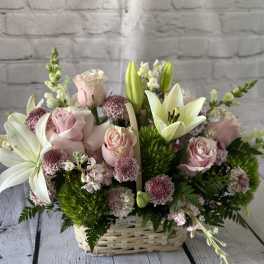 Pink roses and white lilies arranged in a wicker basket