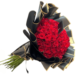 Large bouquet of tightly packed red roses wrapped in ruffled black and gold paper