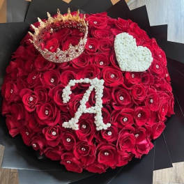 Round bouquet of red roses with a crown and white heart accents