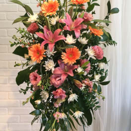 Tall standing floral spray with pink lilies, orange gerberas, and white daisies