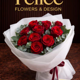 Bouquet of red roses wrapped in white paper with a burgundy ribbon