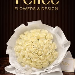 Bouquet of cream roses wrapped in white paper with a ribbon