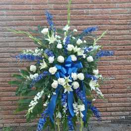 Large standing floral spray with white lilies, roses, and blue flowers