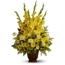 Tall yellow floral arrangement in a brown urn vase