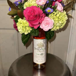 Bouquet in a wine bottle vase with pink roses and purple daisies