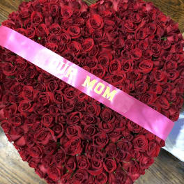 Heart-shaped bouquet of red roses with a pink ribbon