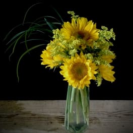 Yellow sunflowers in a clear glass vase with airy filler flowers