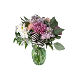 Mixed pink and white bouquet in a green glass vase with a striped ribbon