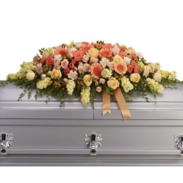Floral casket spray with pink and peach blooms on a silver casket