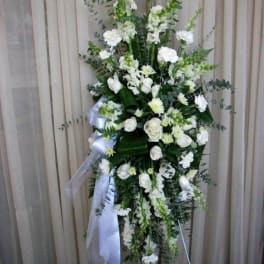 Tall white floral standing spray with ribbon on an easel