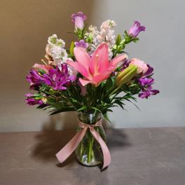 Pink and purple mixed bouquet in a glass vase with a ribbon