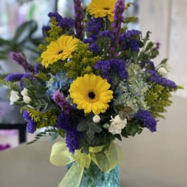 Bright mixed bouquet with yellow gerbera daisies in a blue vase