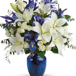 White lilies and blue irises in a blue glass vase