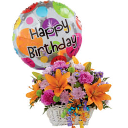 Birthday balloon above a basket of orange lilies and mixed flowers