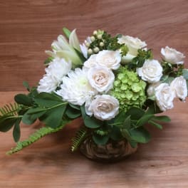 White roses and chrysanthemums arranged in a low glass vase