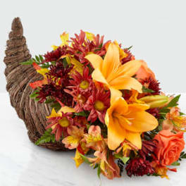 Autumn flower arrangement in a woven cornucopia basket with orange lilies and red blooms