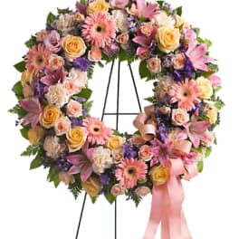 Pastel floral wreath with roses, lilies, and gerbera daisies on a stand