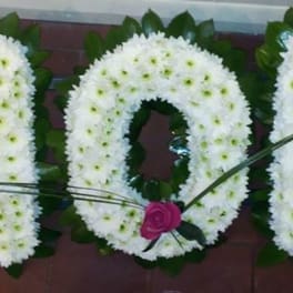 White floral letters spelling MOM with pink roses accenting the design