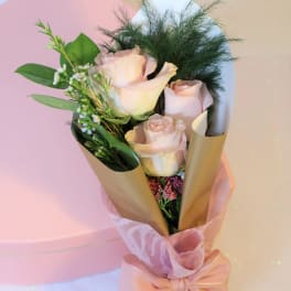 Bouquet of pale pink roses wrapped in gold paper with a pink ribbon