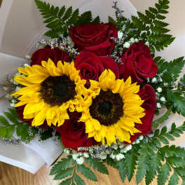Bouquet of red roses and yellow sunflowers wrapped in white paper