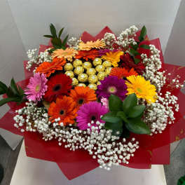Colorful gerbera daisy bouquet with baby’s breath and gold chocolates