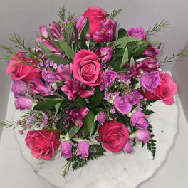 Pink and purple rose bouquet on a white round base