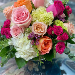Bouquet of pink, orange, and white roses with pale hydrangeas