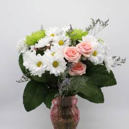 Pink roses and white daisies arranged in a pink glass vase
