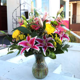 Pink lilies and yellow chrysanthemums in a glass vase