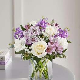 Bouquet of white roses, purple flowers, and pink lilies in a glass vase