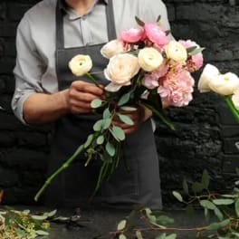 Florist holding a bouquet of pale pink and cream ranunculus