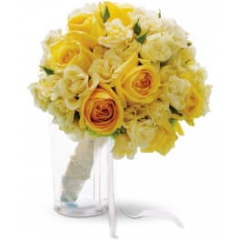 Yellow and white rose bouquet in a clear glass vase with ribbon