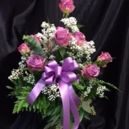 Pink rose bouquet with white filler flowers and a purple ribbon