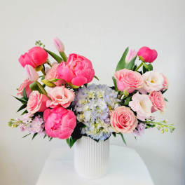 Pink and white floral arrangement in a white ribbed vase