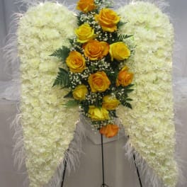 White floral standing spray with yellow roses on a metal easel