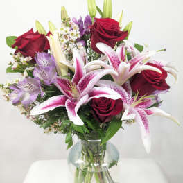 Bouquet of red roses and pink lilies in a clear glass vase