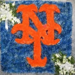 Blue floral tribute with orange monogram and white flower clusters