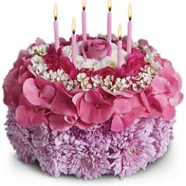 Pink floral cake with lit candles on top
