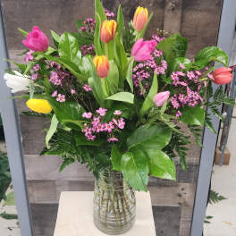 Mixed tulip bouquet with pink and yellow blooms in a glass vase