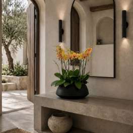 Potted orchid arrangement with yellow and peach blooms in a black bowl planter