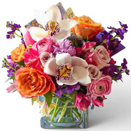 Mixed bouquet with roses, orchids, and purple flowers in a glass vase