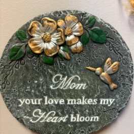 Round decorative plaque with gold flowers and the words "Mom your love makes my Heart bloom"