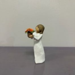 Small figurine of a child holding a tiny flower pot