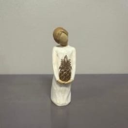 Small figurine in a white dress holding a pinecone