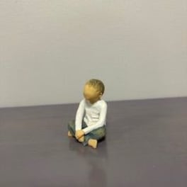 Small seated figurine of a child on a plain surface