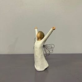 Small angel figurine in a white dress with raised arms