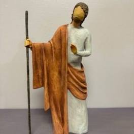 Small figurine of a robed person holding a staff